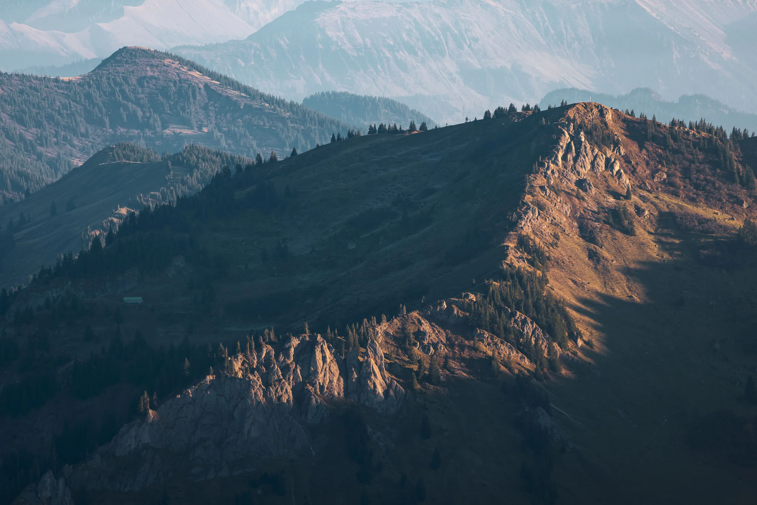 Ein markanter herbstlicher Grat liegt ruhig vor schattigen Bergketten