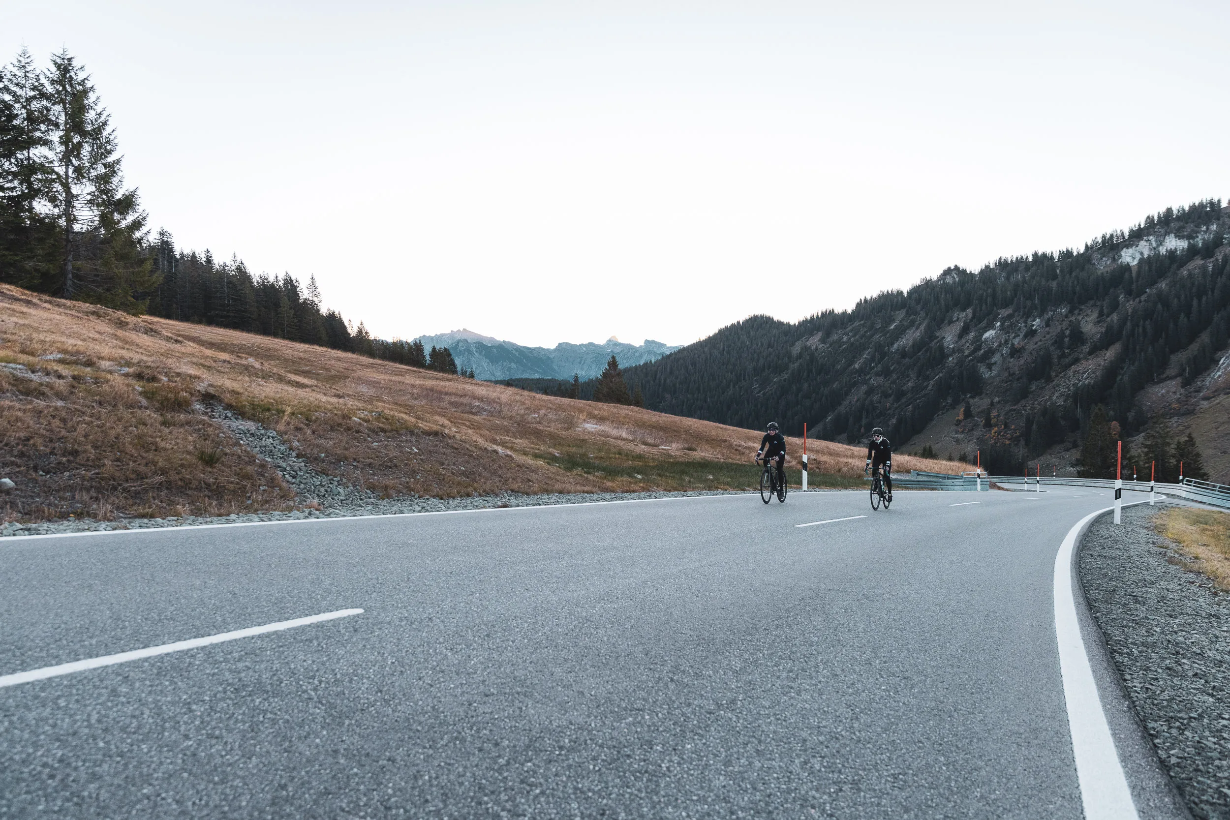 Zwei Rennradfahrerinnen auf einer breiten Kurve der Passstraße