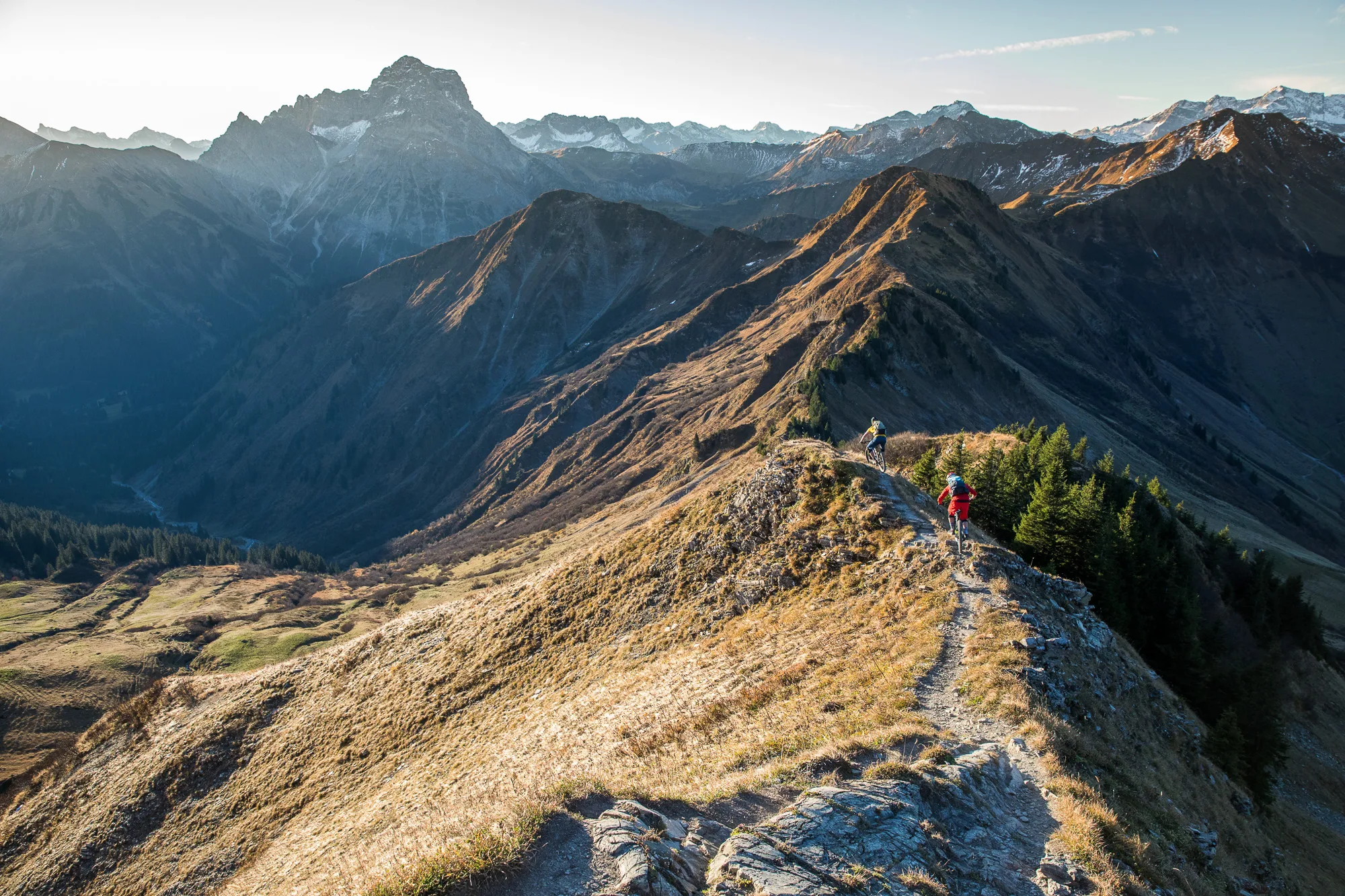 Zwei Mountainbiker fahren hintereinander über einen trockenen Bergkamm im Kleinwalsertal