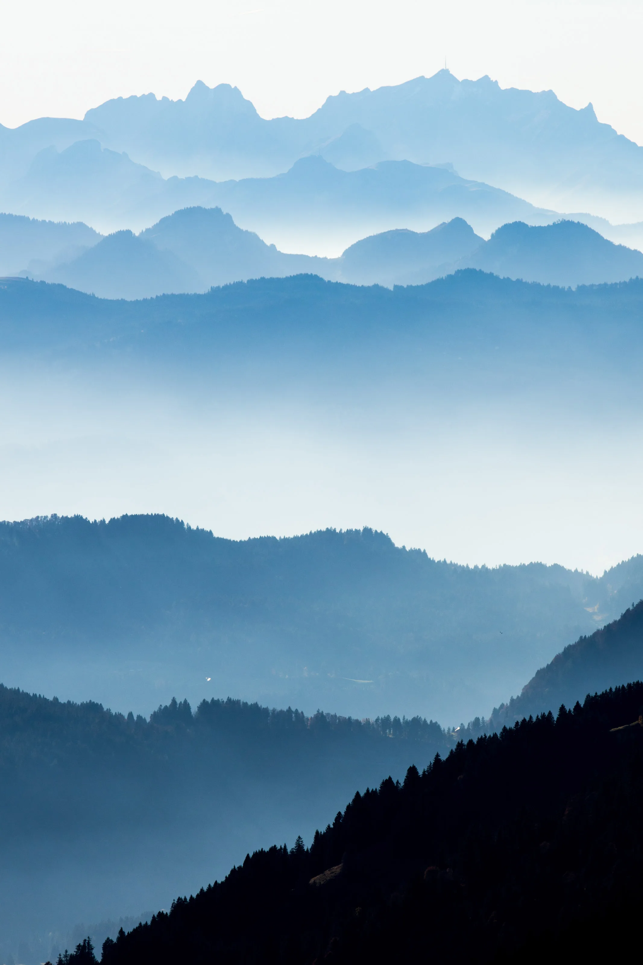 Hochformat mit gestaffelten Bergketten und bewaldeten Hängen.