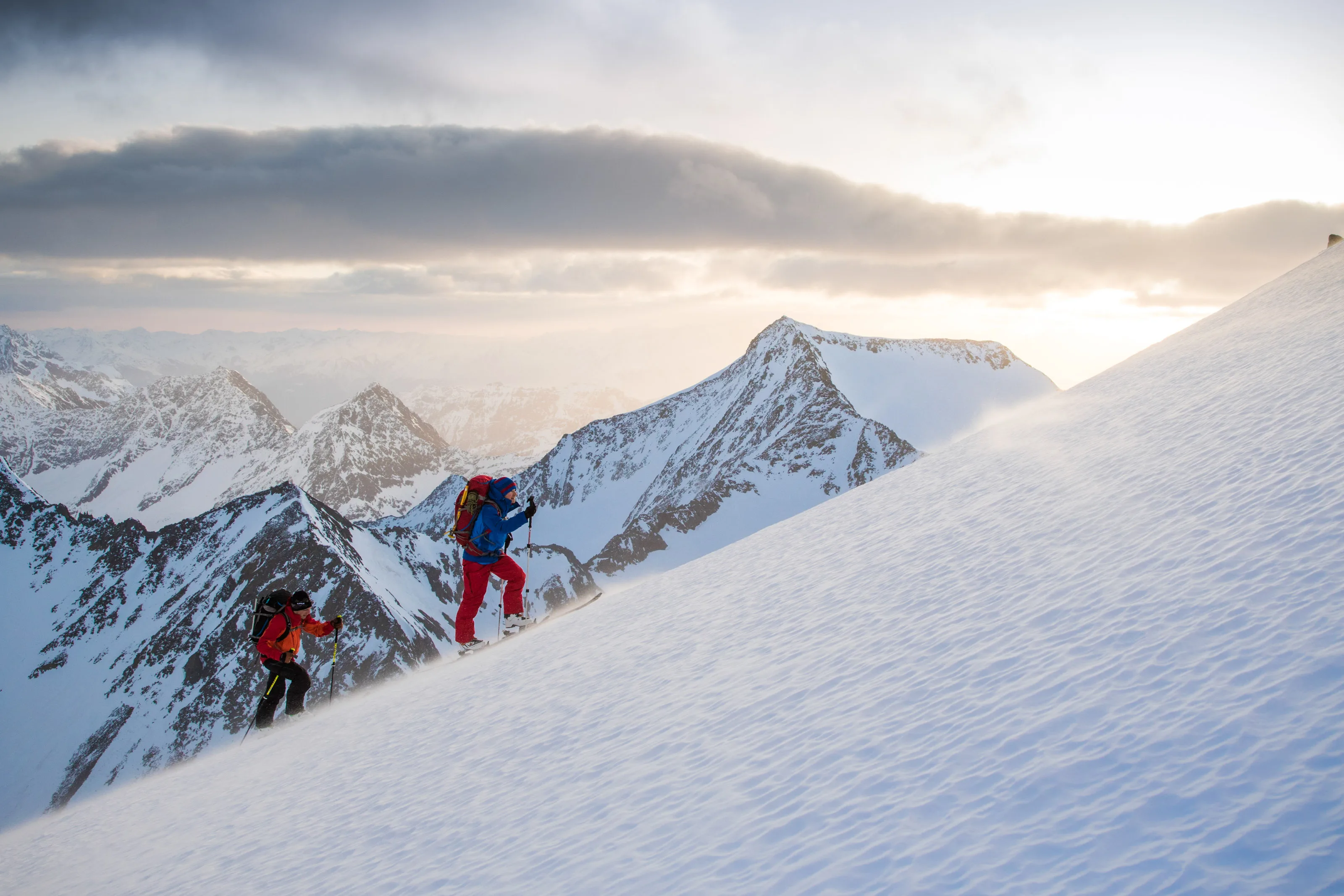 Florian Häusler und Tobias Baur queren mit Tourenski einen steilen Hang über dem Wolkenmeer