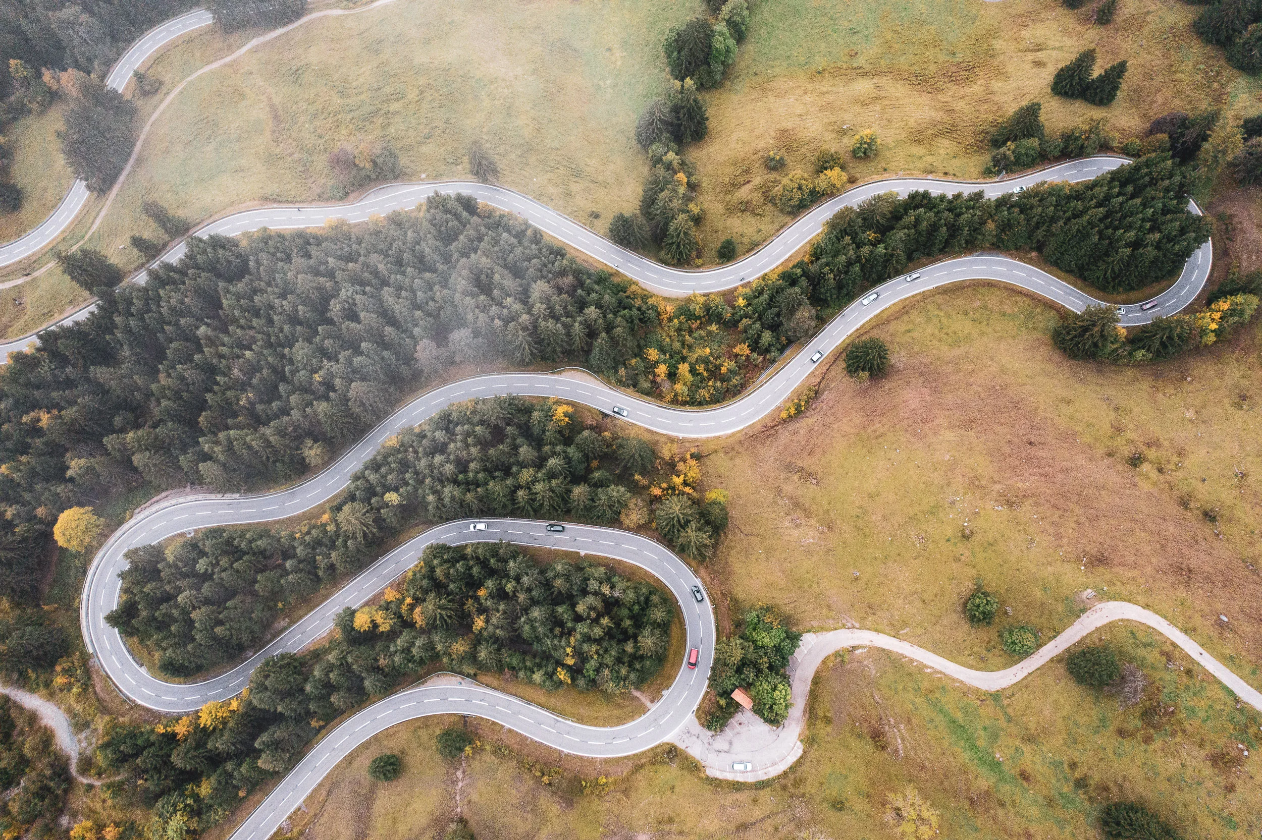Die Passstraße am Oberjoch zieht in weiten Serpentinen durch herbstliche Wiesen und Wald.