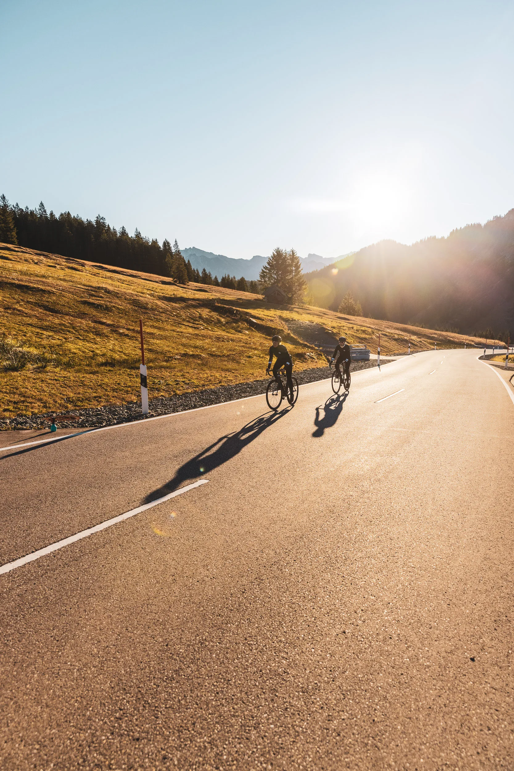 Zwei Rennradfahrerinnen fahren mit langen Schatten durch das Abendlicht