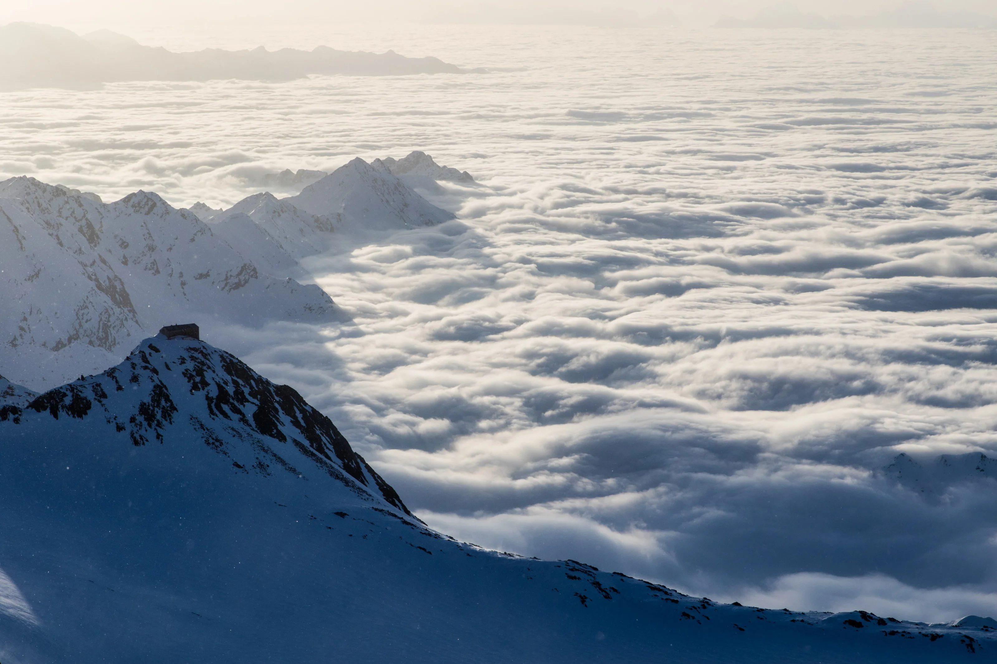 Weite Wolkendecke liegt zwischen schneebedeckten Bergketten in den Tiroler Alpen
