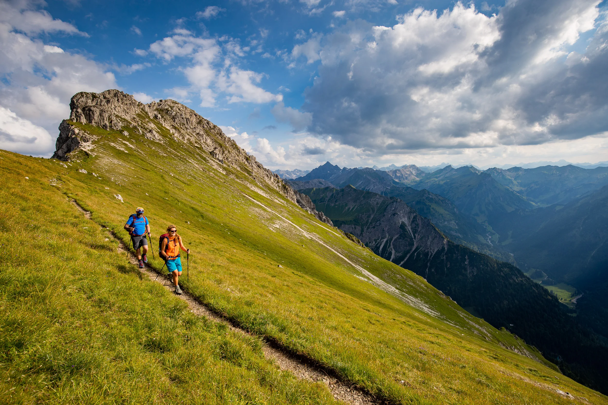 Caroline Nantke und Harald Dreyer wandern auf einem schmalen Pfad unter einem Felsgipfel