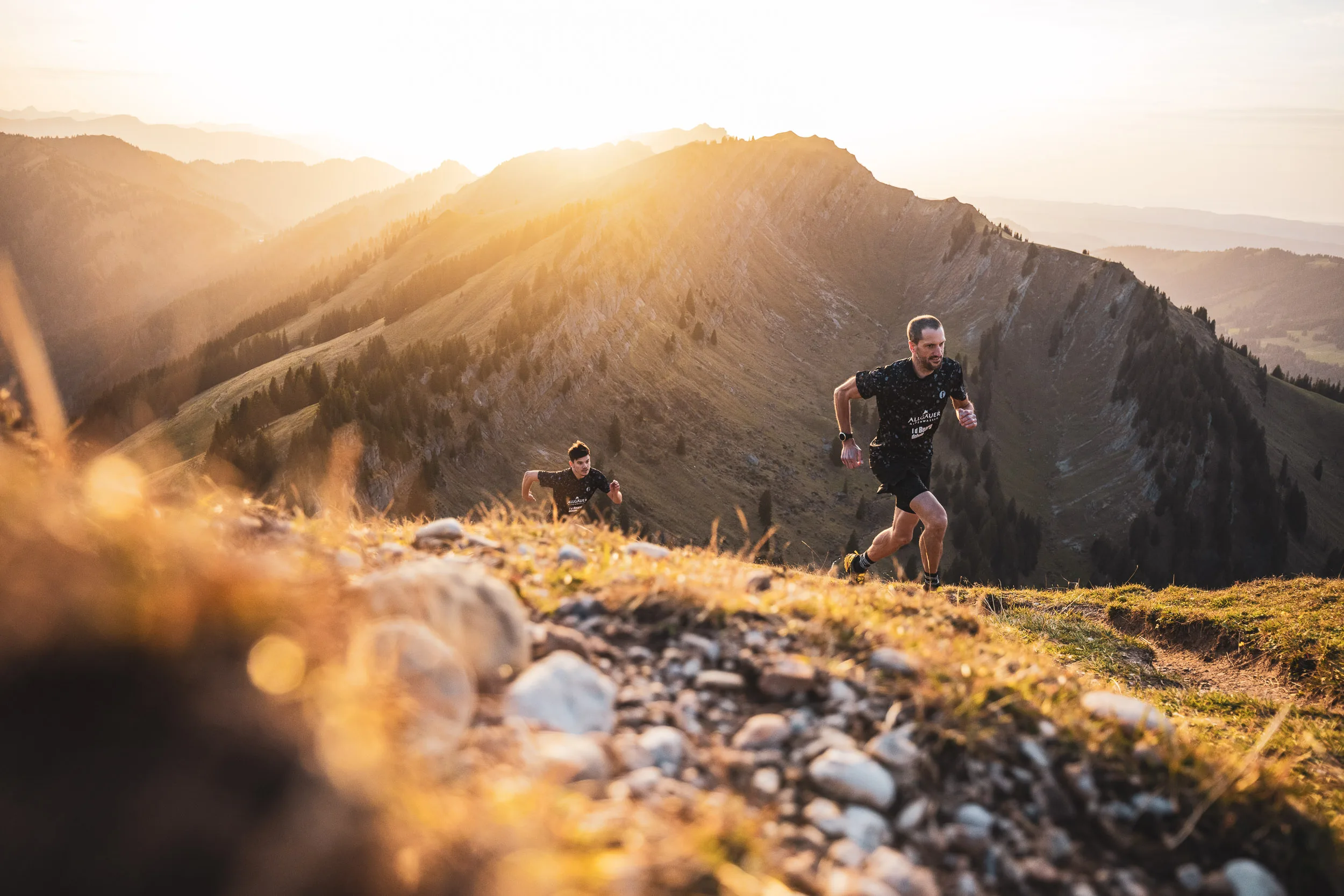 Trailrunner auf einem Gratweg mit Mineralwasserflaschen im Vordergrund