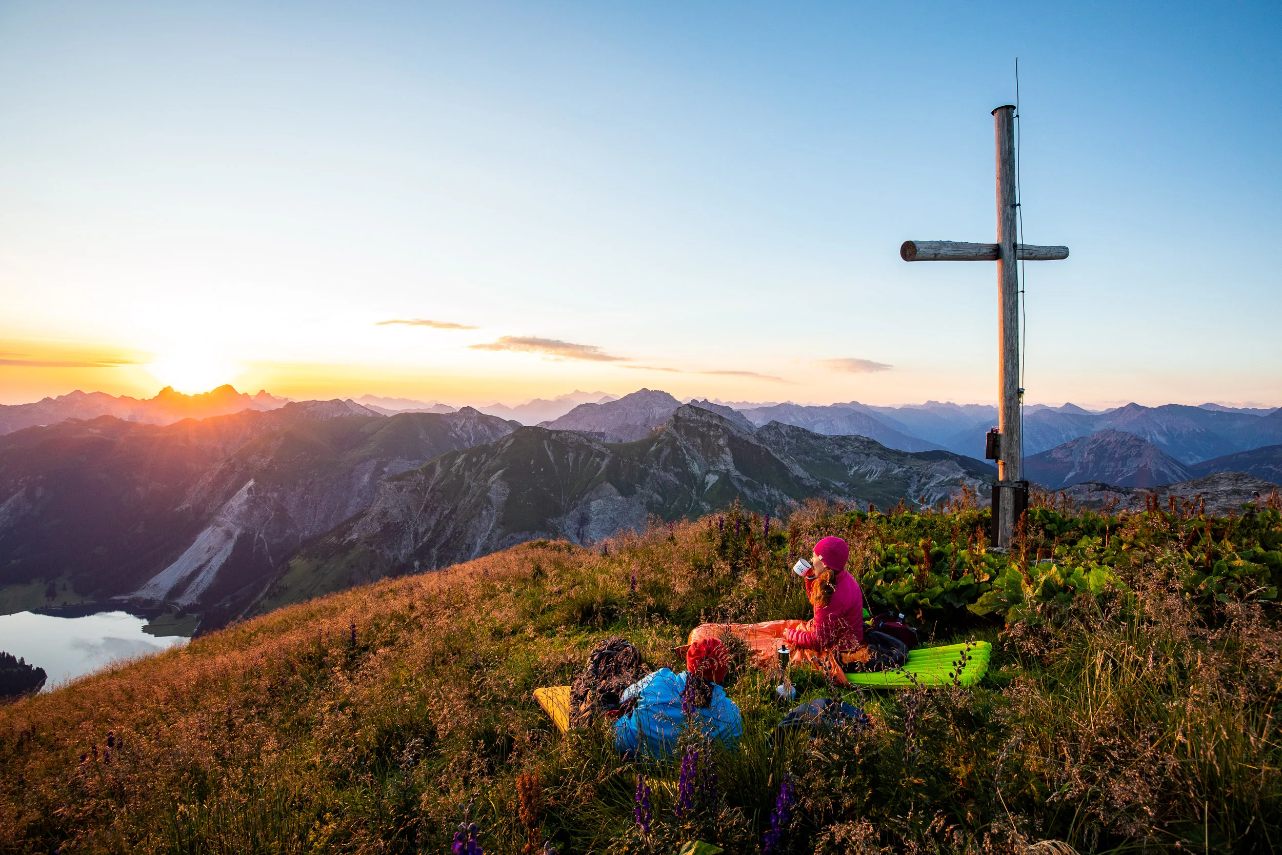 Caroline Nantke und Harald Dreyer rasten am Gipfelkreuz auf einer blühenden Bergwiese