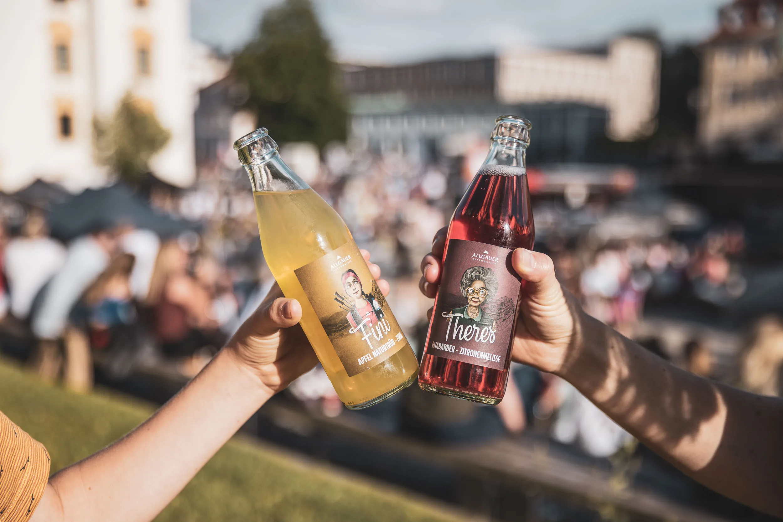 Zwei Personen stossen mit Flaschen auf dem Street Food Markt an.