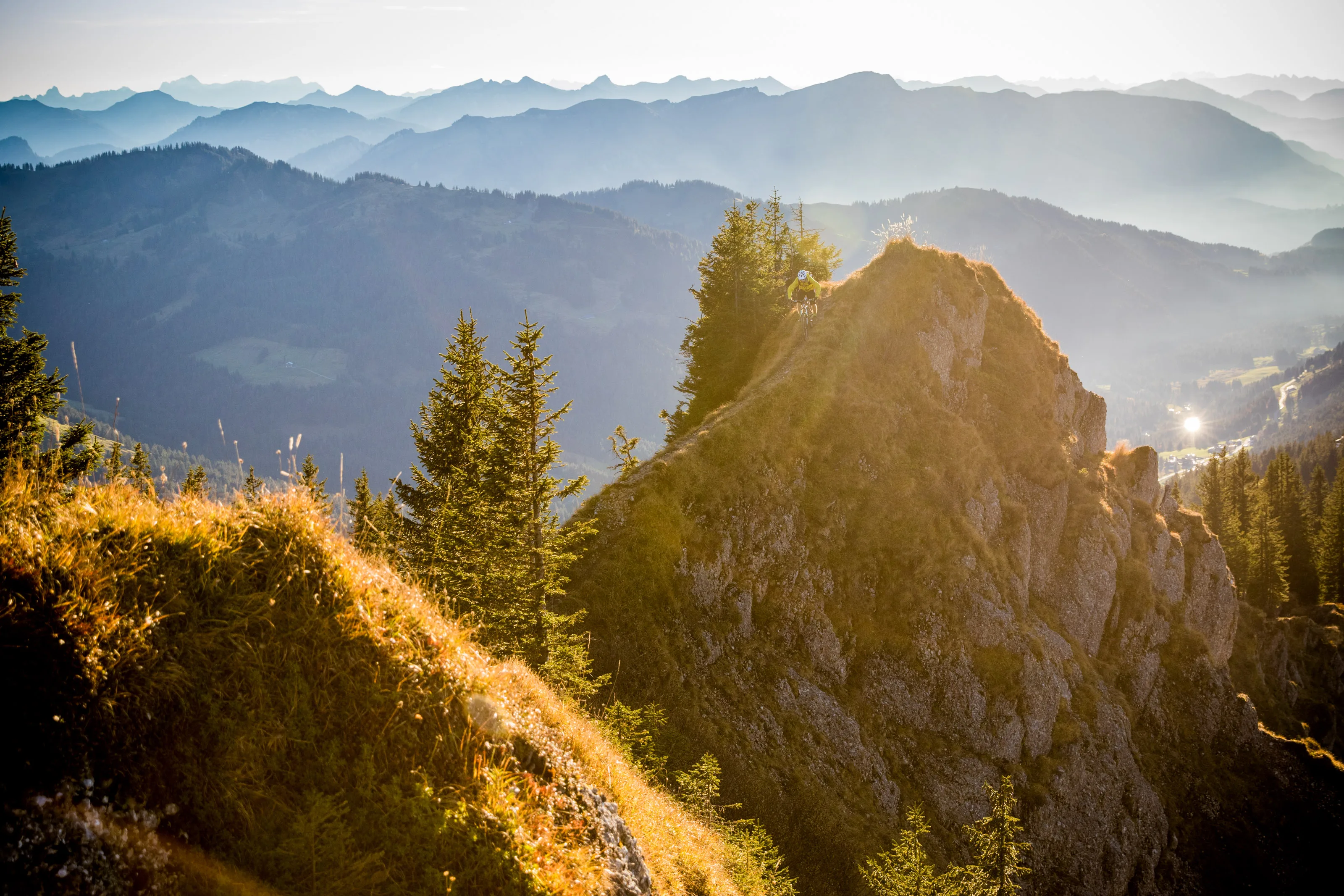 Florian Häusler fährt mit dem Mountainbike über einen schmalen Felsgrat vor den Allgäuer Alpen.