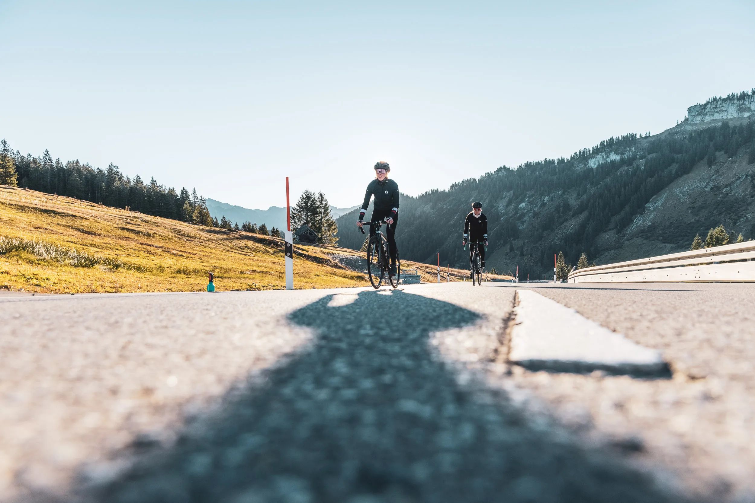 Zwei Rennradfahrerinnen nähern sich auf einer Passstraße im Herbst