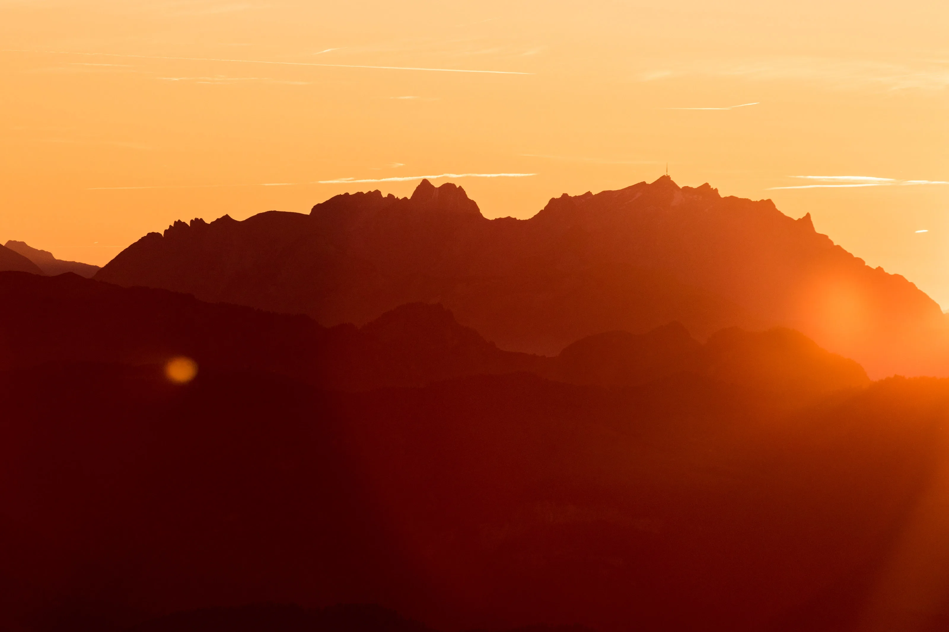 Bergsilhouette vor orangefarbenem Himmel bei Sonnenuntergang.