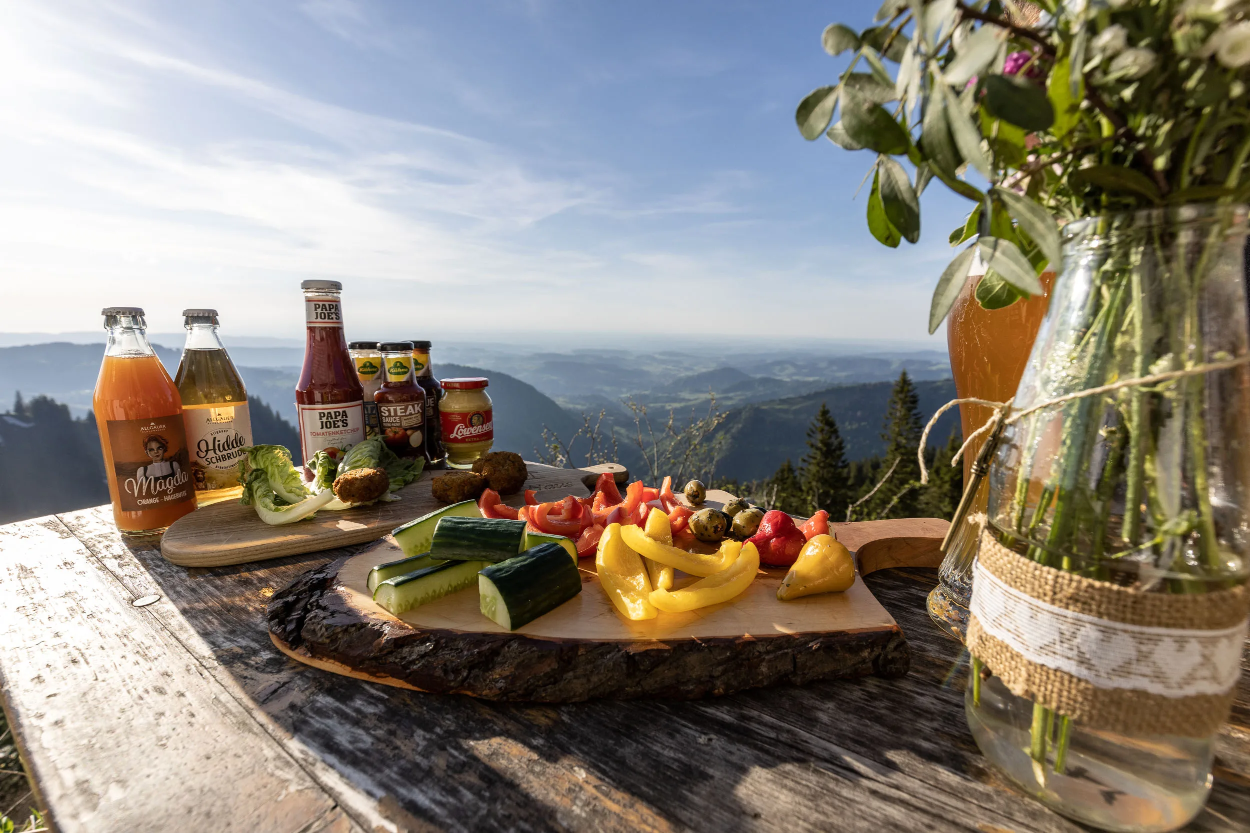 Brotzeit und Getränke auf einem Tisch mit Bergblick am Hochgrat.