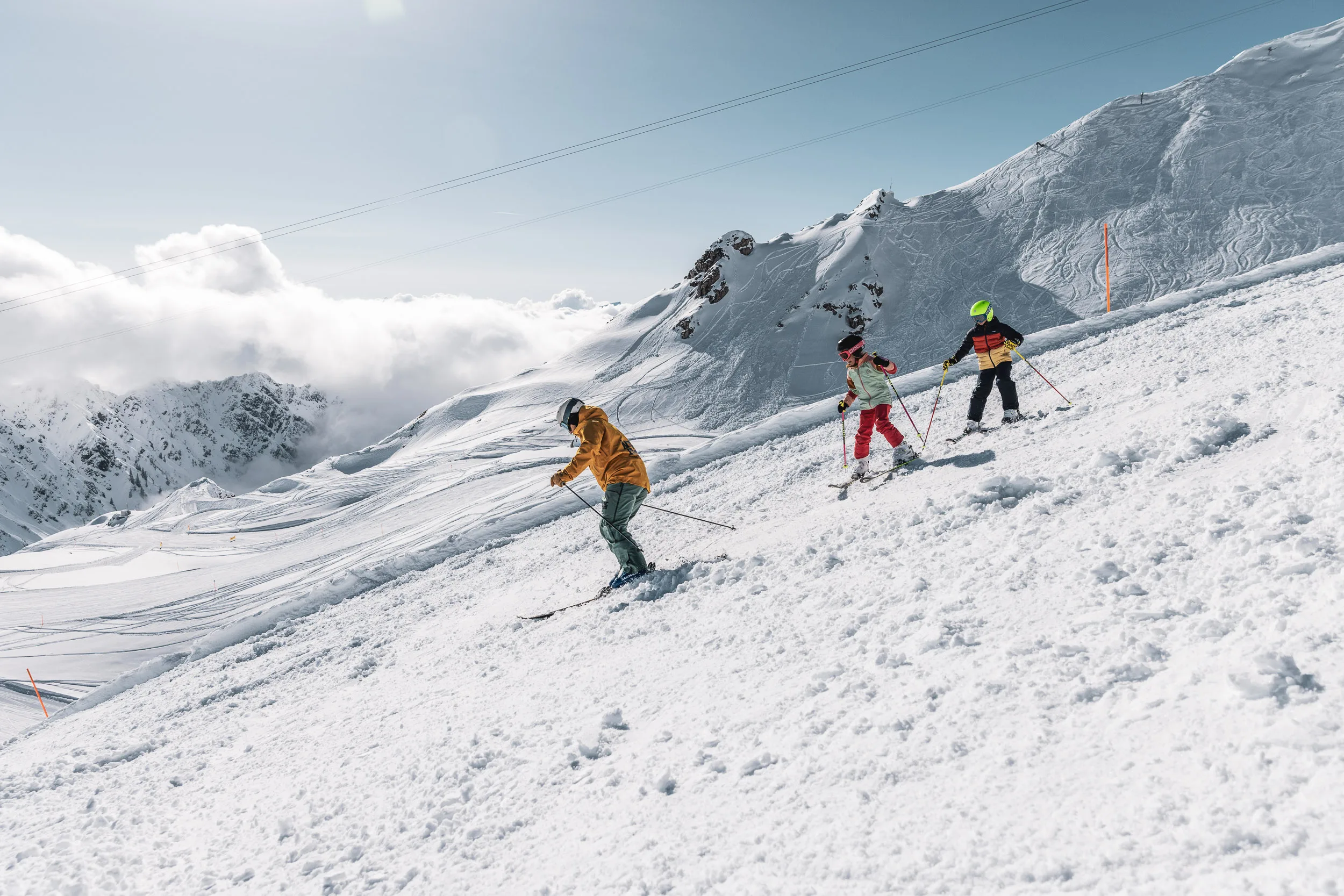 Skilehrer führt eine Gruppe über eine sonnige Piste unter Berggipfeln