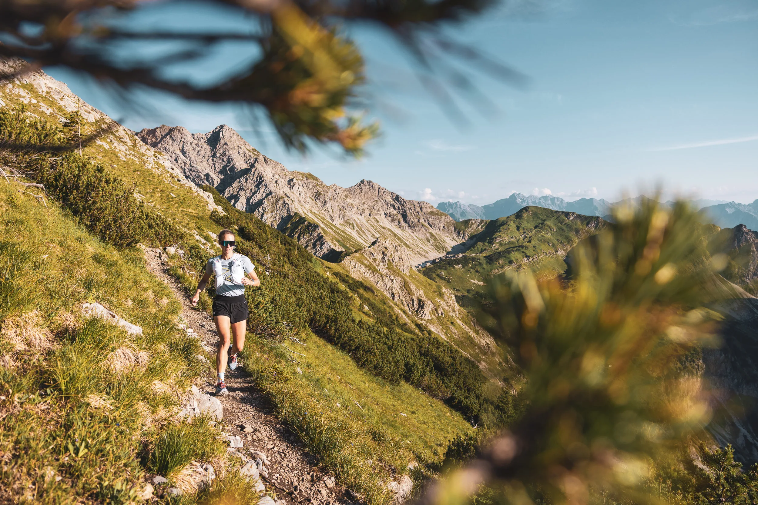 Trailrunnerin auf einem alpinen Pfad zwischen Latschenkiefern