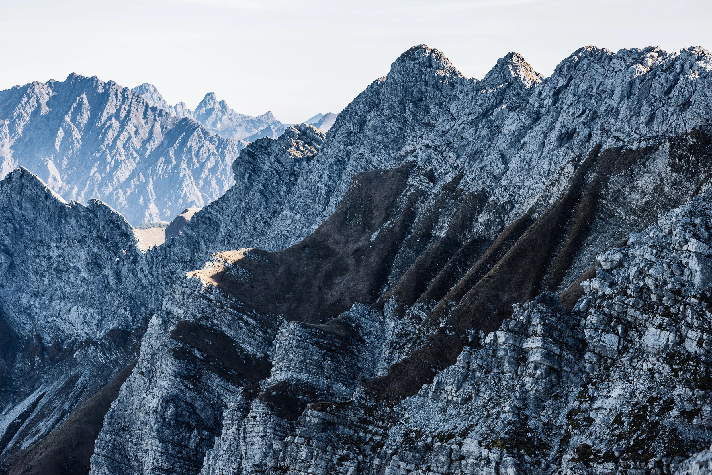 Gezackte Kalkgrate der Allgäuer Alpen liegen im klaren Herbstlicht über tiefen Schatten.