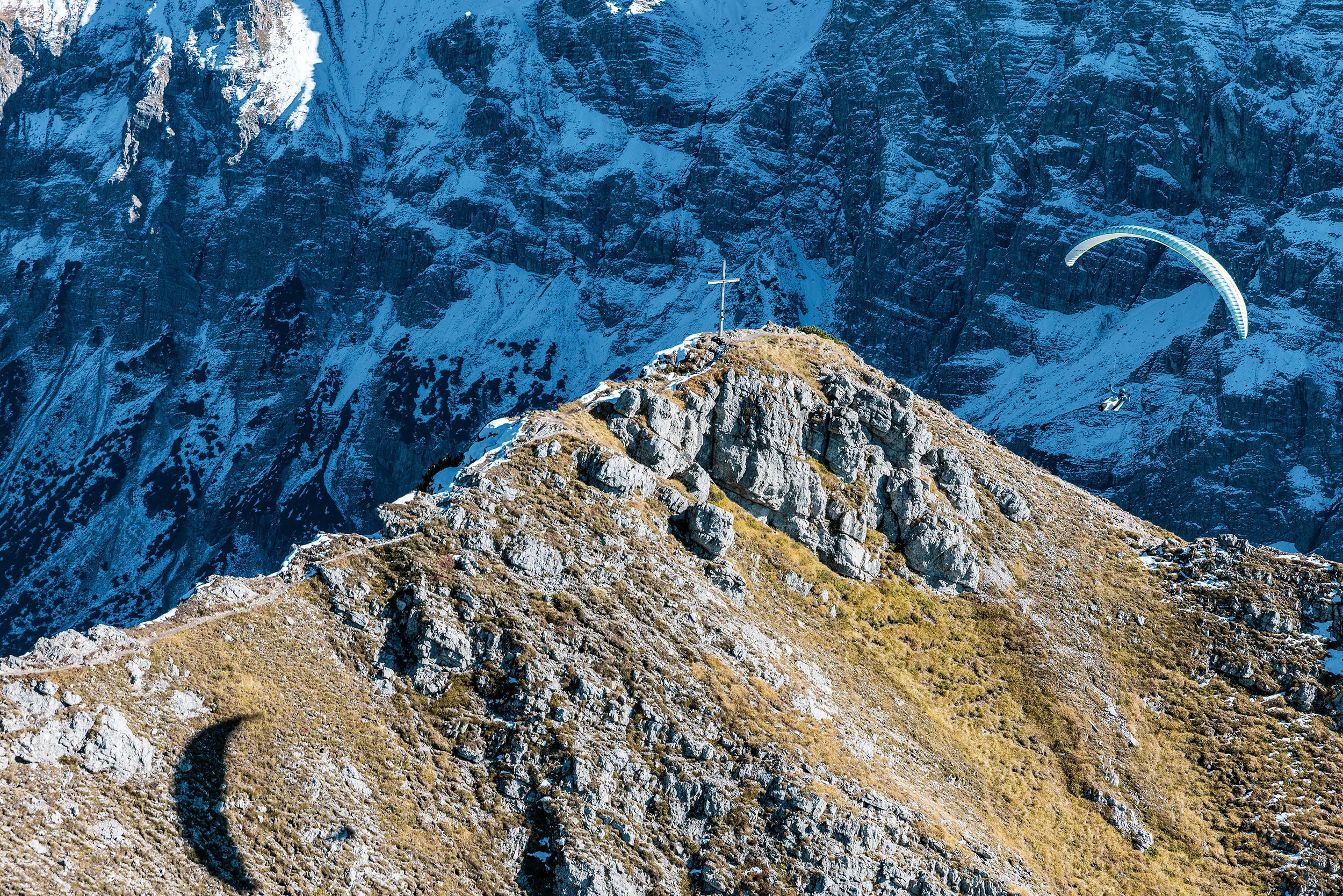Michael Schnetzer fliegt mit dem Gleitschirm an einem herbstlichen Grat oberhalb von Oberstdorf.