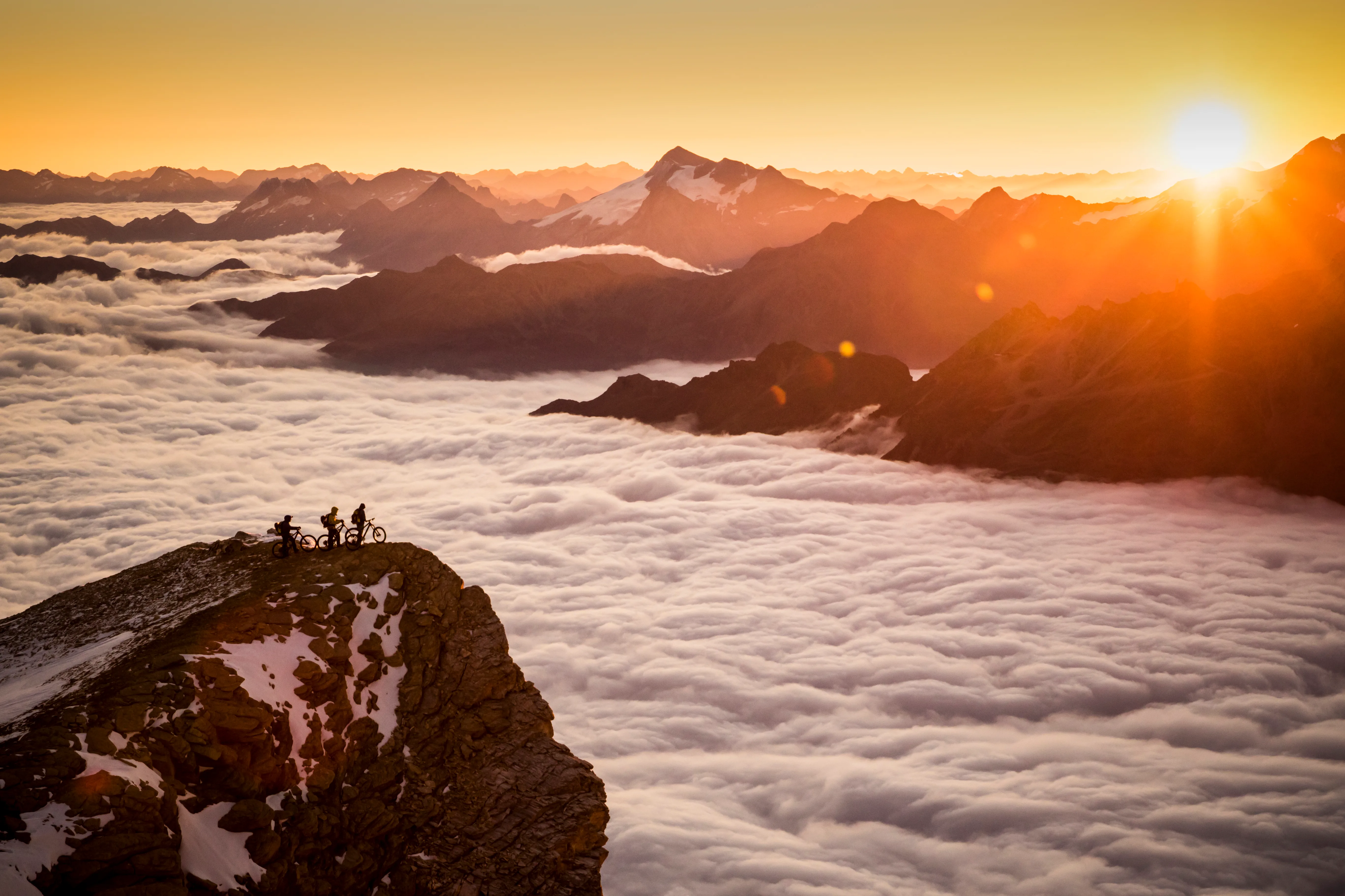 Mountainbiker stehen mit ihren Rädern über einem Wolkenmeer am Barrhorn.