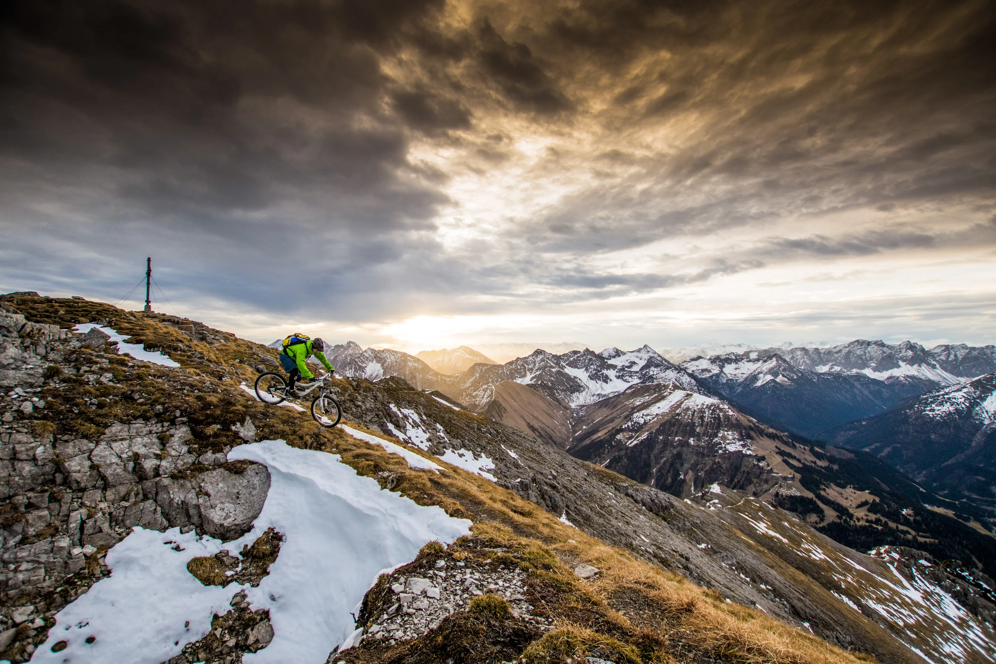Florian Bergmann fährt mit dem Mountainbike über einen felsigen Gipfelgrat am Thaneller.