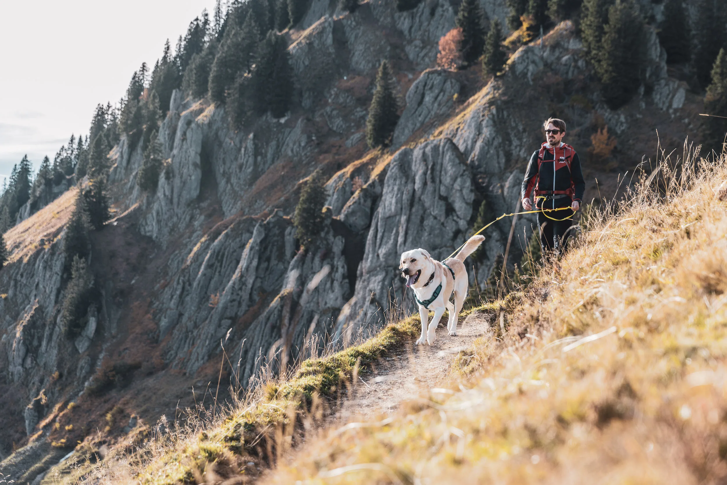 Hund Oskar führt auf einem schmalen Pfad, während Andreas Kögel durch felsiges Gelände folgt