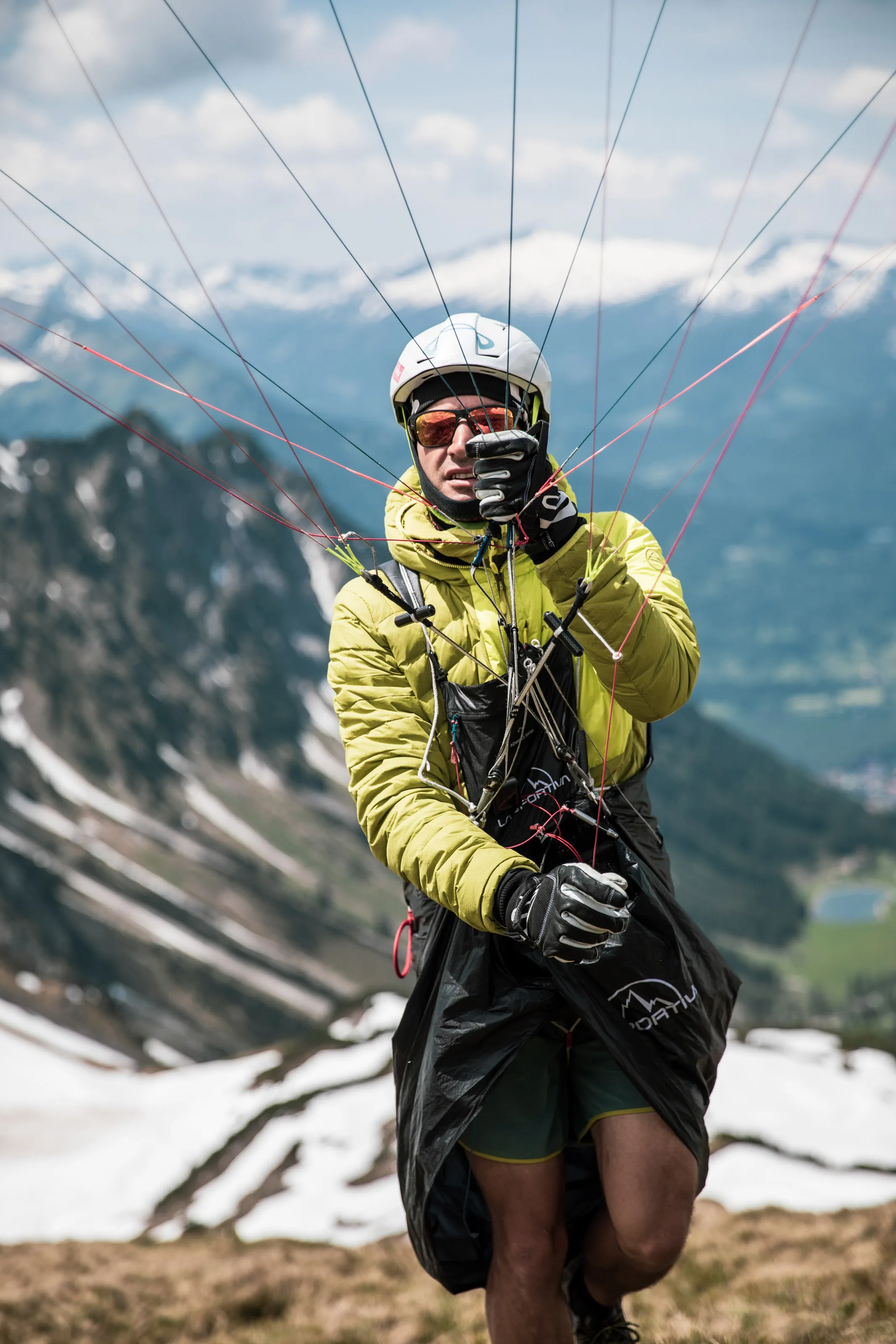 Michael Lacher steht mit Helm und Gurtzeug auf dem Hang; die Gleitschirmleinen hängen vor ihm.