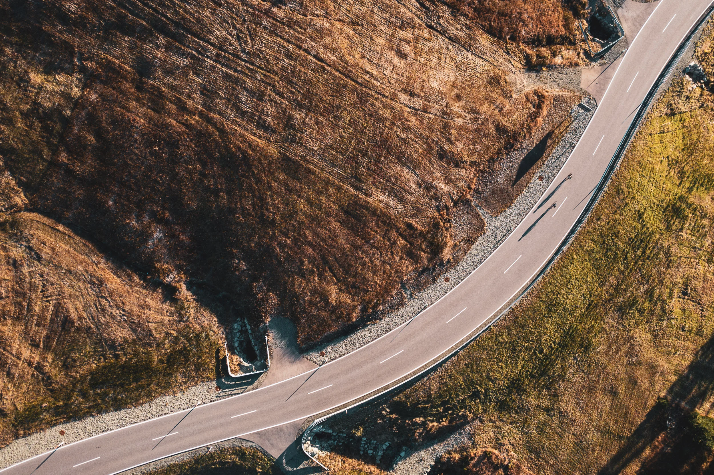 Luftaufnahme einer Rennradstraße in einer weiten Kehre am Riedbergpass im Herbst
