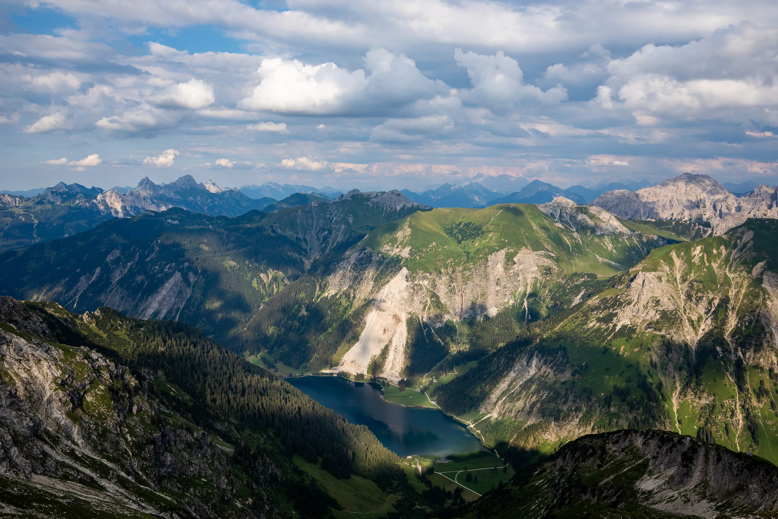 Grüne und graue Allgäuer Bergketten unter leuchtenden Wolken