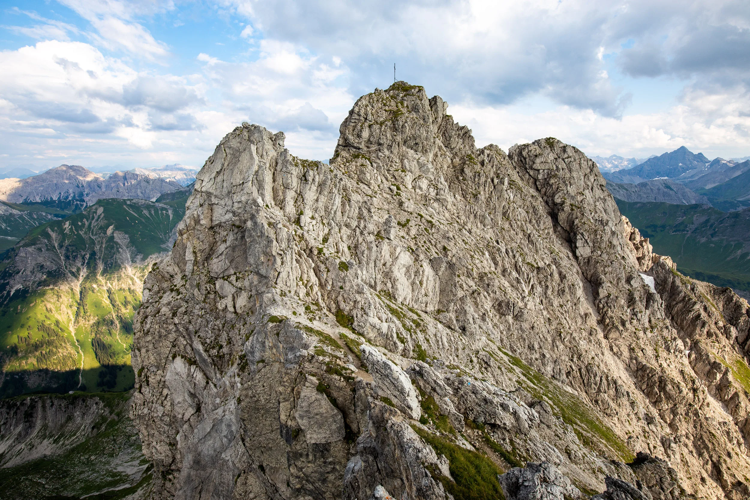 Schroffe Felszacken heben sich vor den fernen Gipfeln der Allgäuer Alpen ab