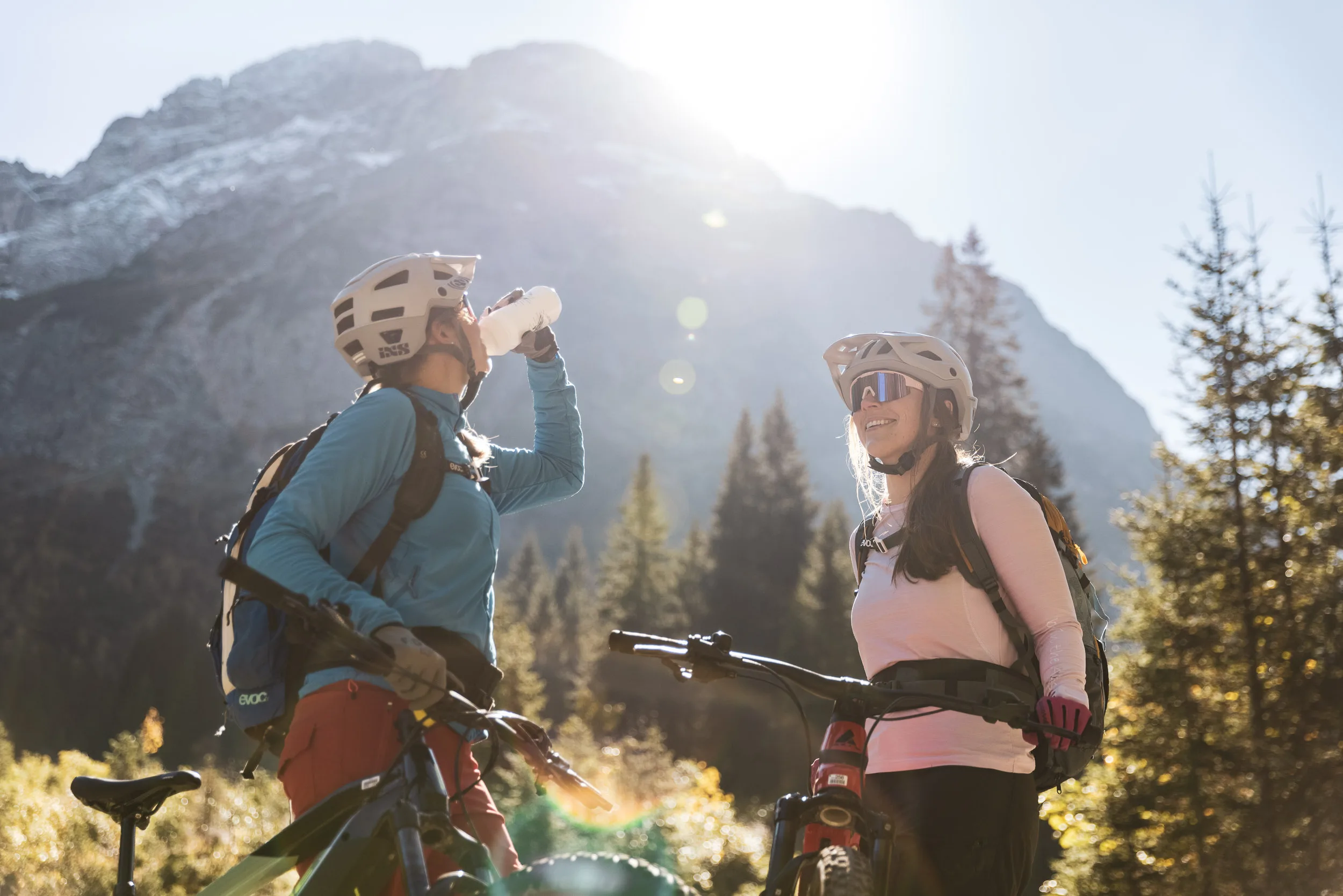Andrea Geiger trinkt bei einer Pause neben ihrem Mountainbike im Gegenlicht