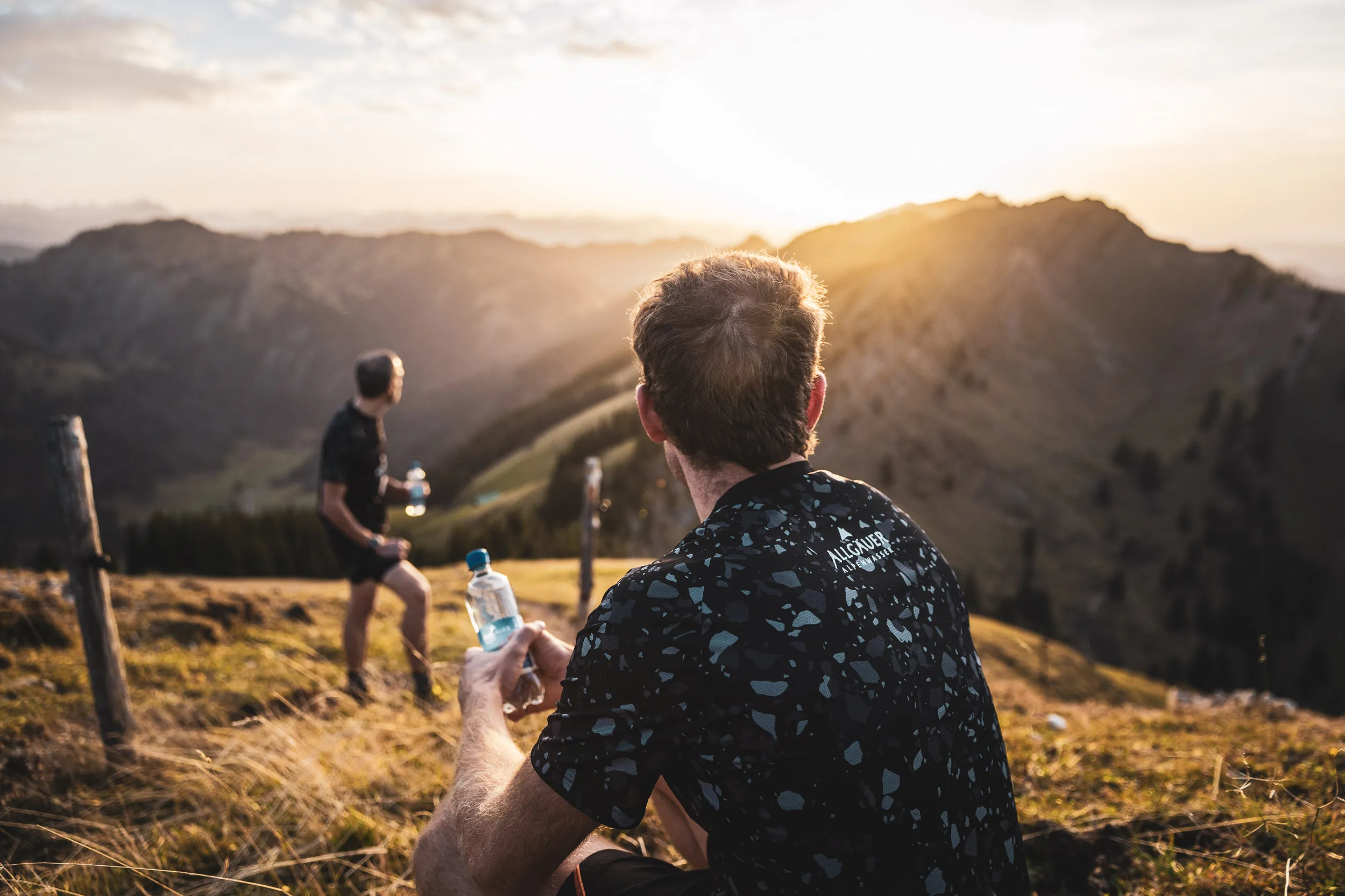Trailrunner sitzt mit Wasserflasche und Blick in die abendliche Nagelfluhkette