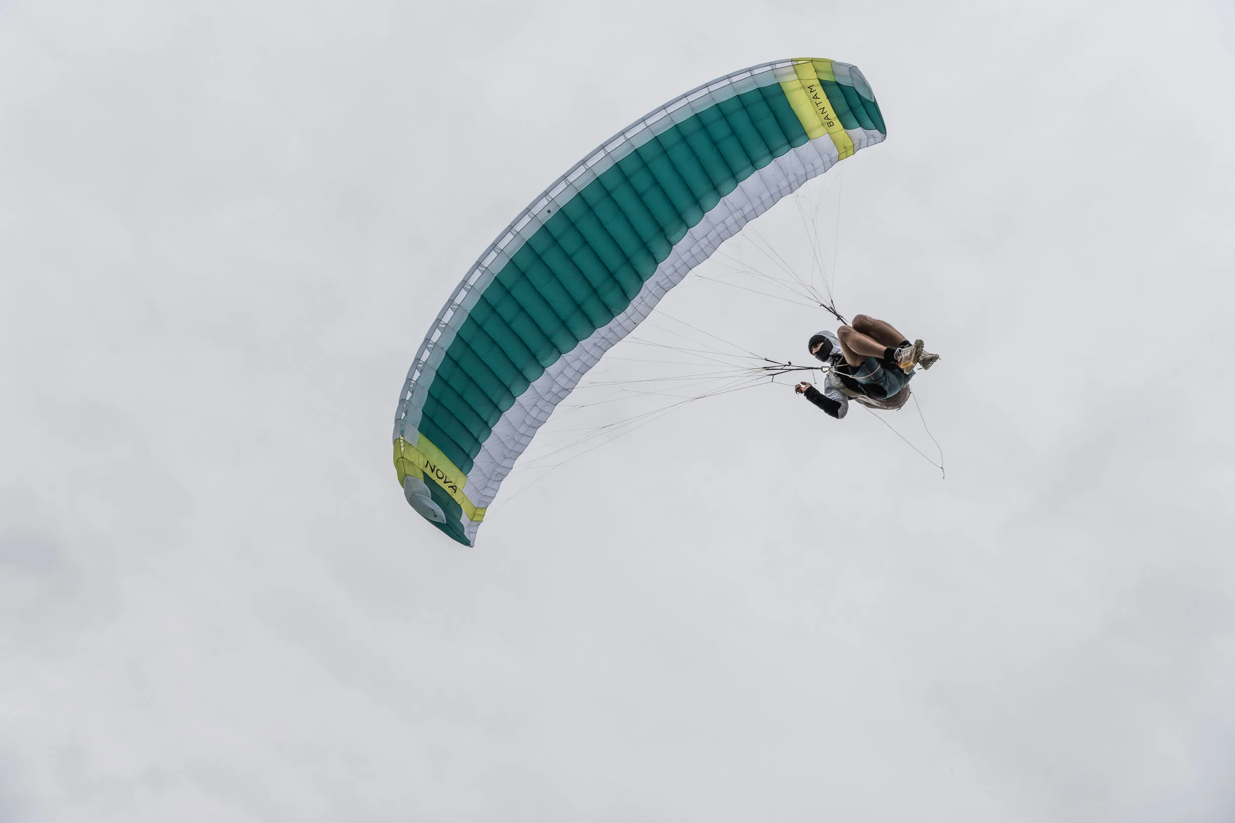 Michael Lacher fliegt mit dem Gleitschirm vor dicht bewölktem Himmel
