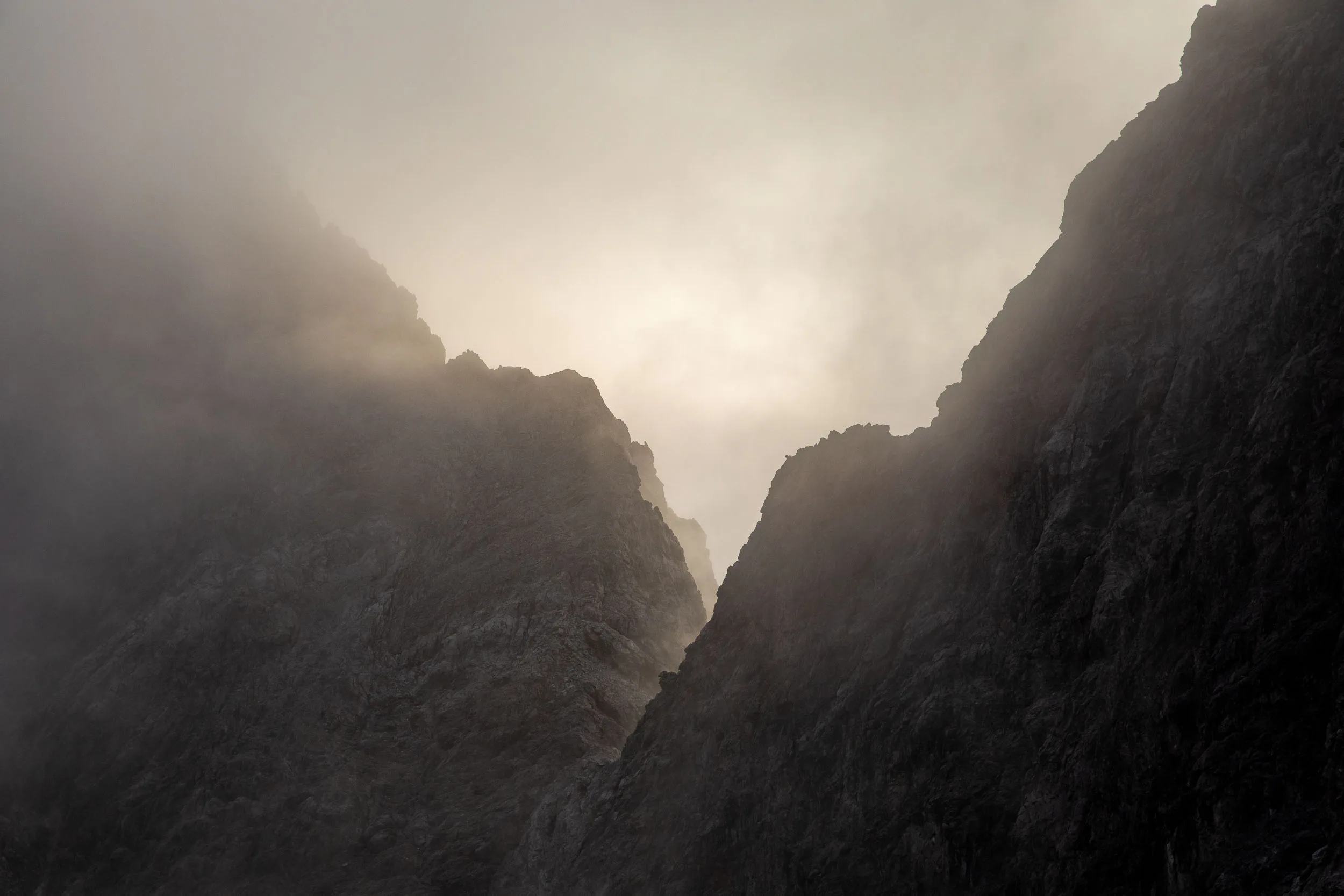 Nebel zieht durch eine schmale Felsrinne zwischen dunklen Bergwänden