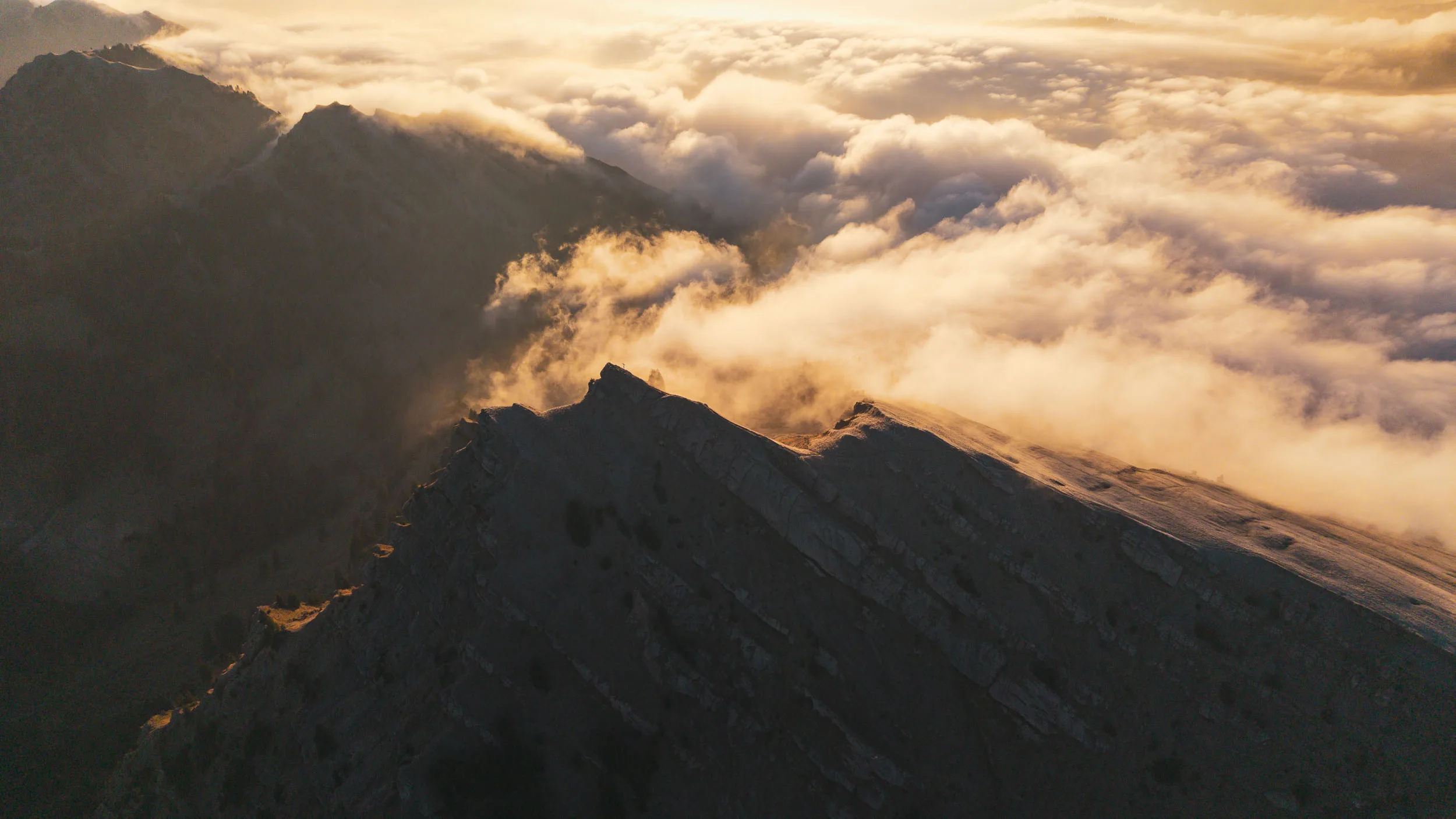Wolken steigen an einem steilen Nagelfluhgrat im warmen Morgenlicht auf
