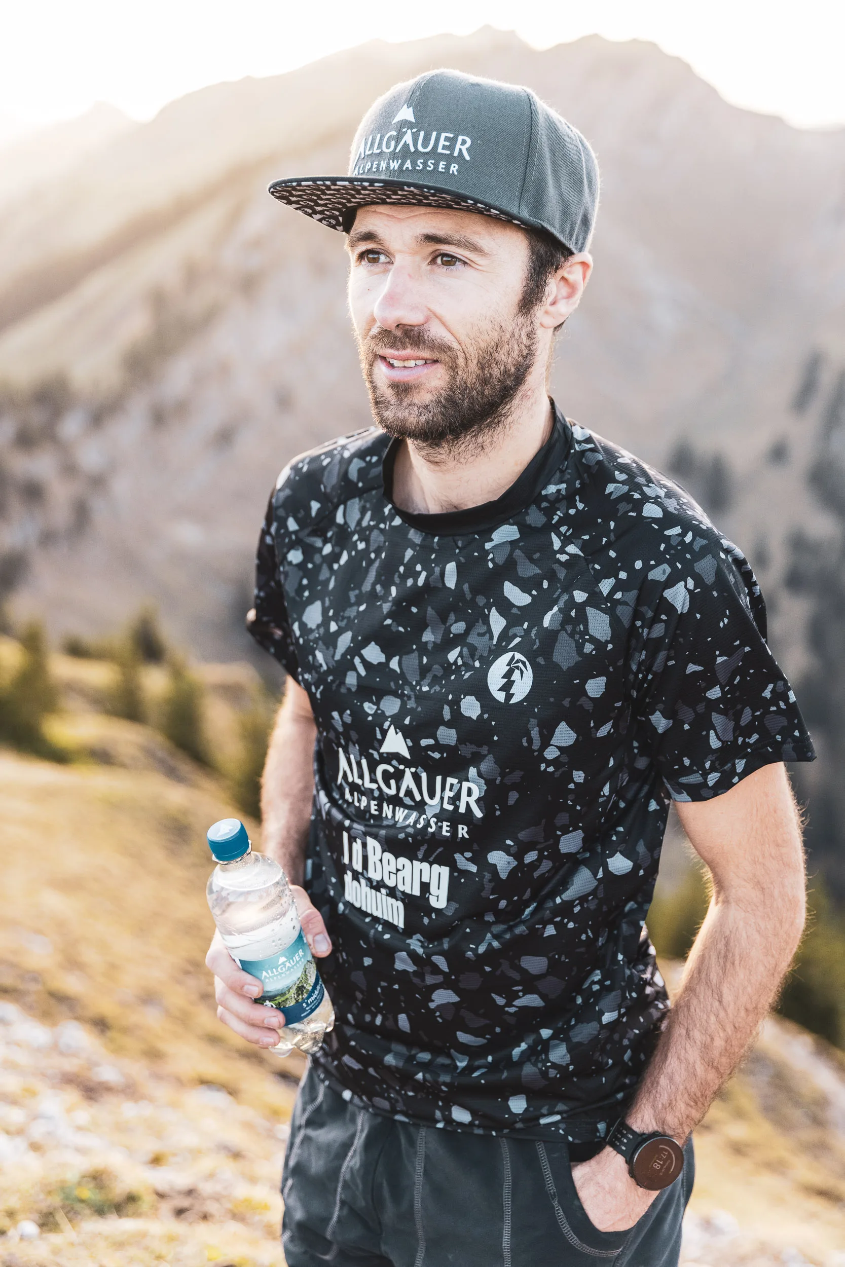 Trailrunner mit schwarzem Laufshirt und Wasserflasche vor der Nagelfluhkette