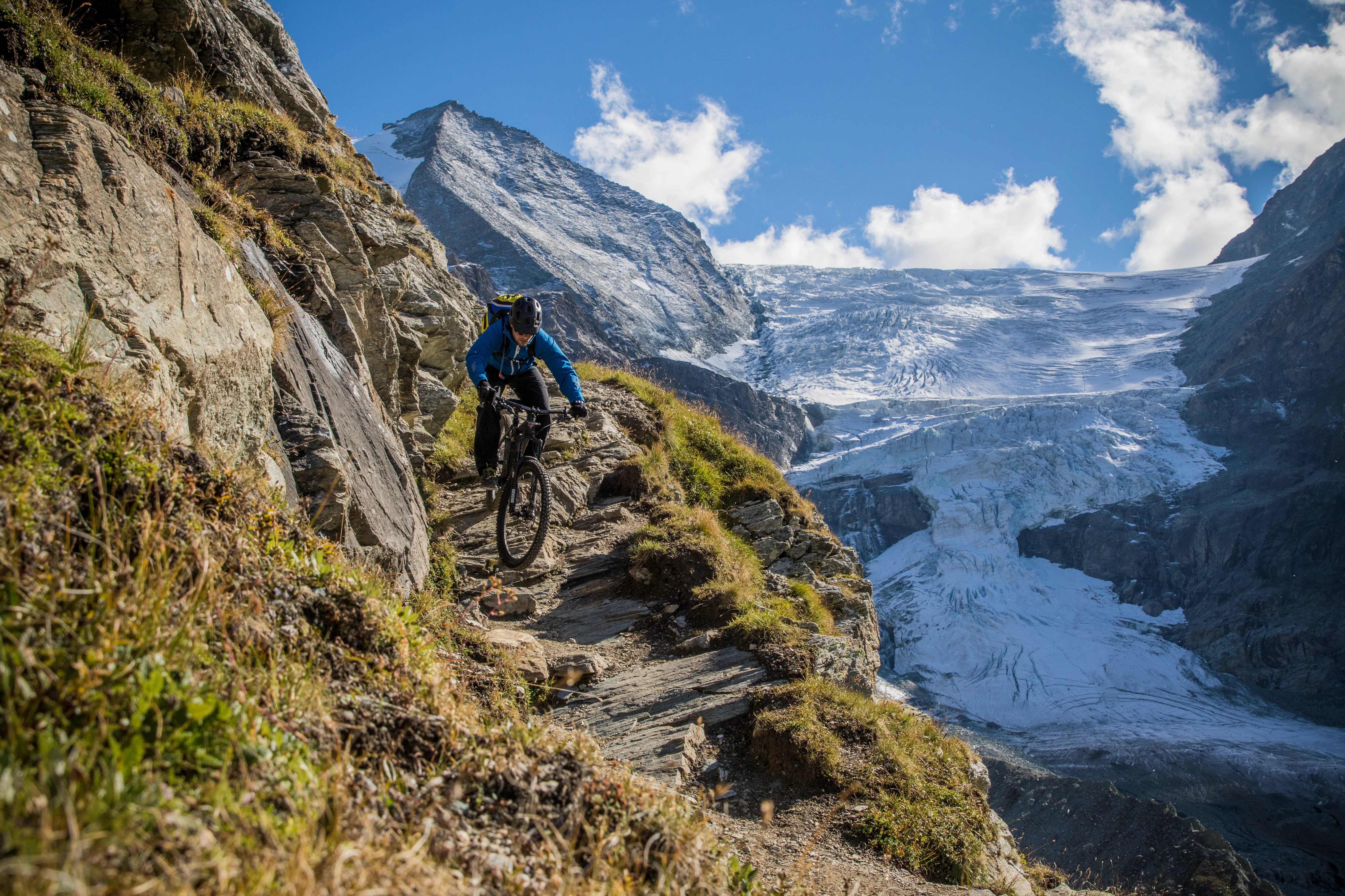 Florian Bergmann fährt auf einem schmalen Trail vor vergletscherten Gipfeln im Wallis.