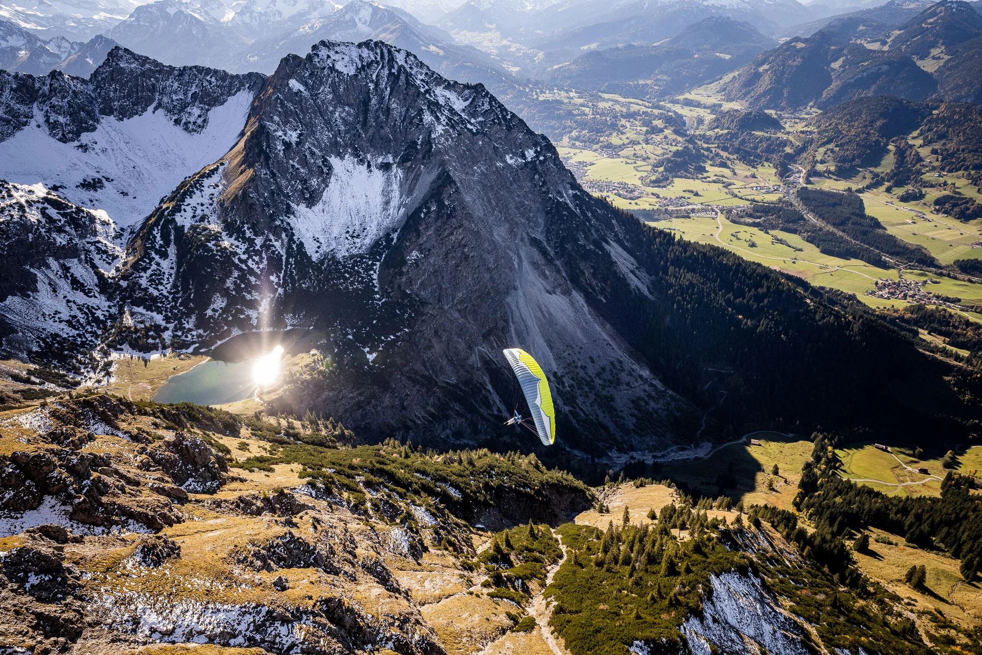 Michael Schnetzer gleitet mit dem Gleitschirm über dem Geisalpsee bei Oberstdorf im Herbstlicht.