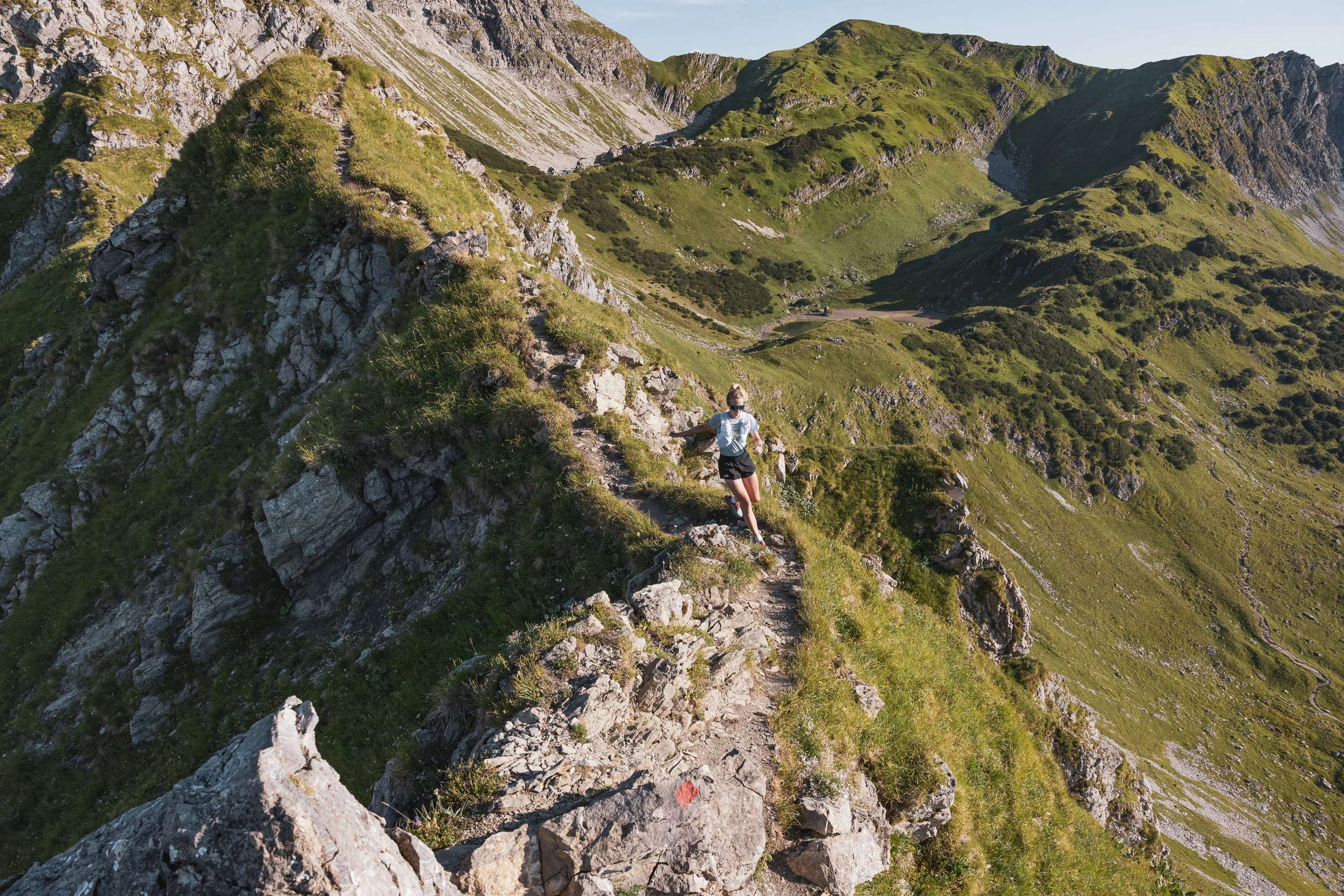 Trailrunnerin auf einem felsigen Berggrat vor den Allgäuer Alpen