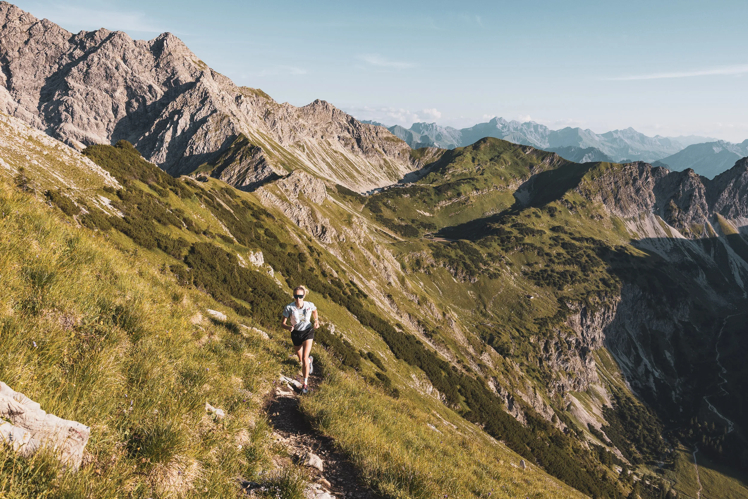 Trailrunnerin auf einem ausgesetzten Bergpfad über einem tiefen Tal