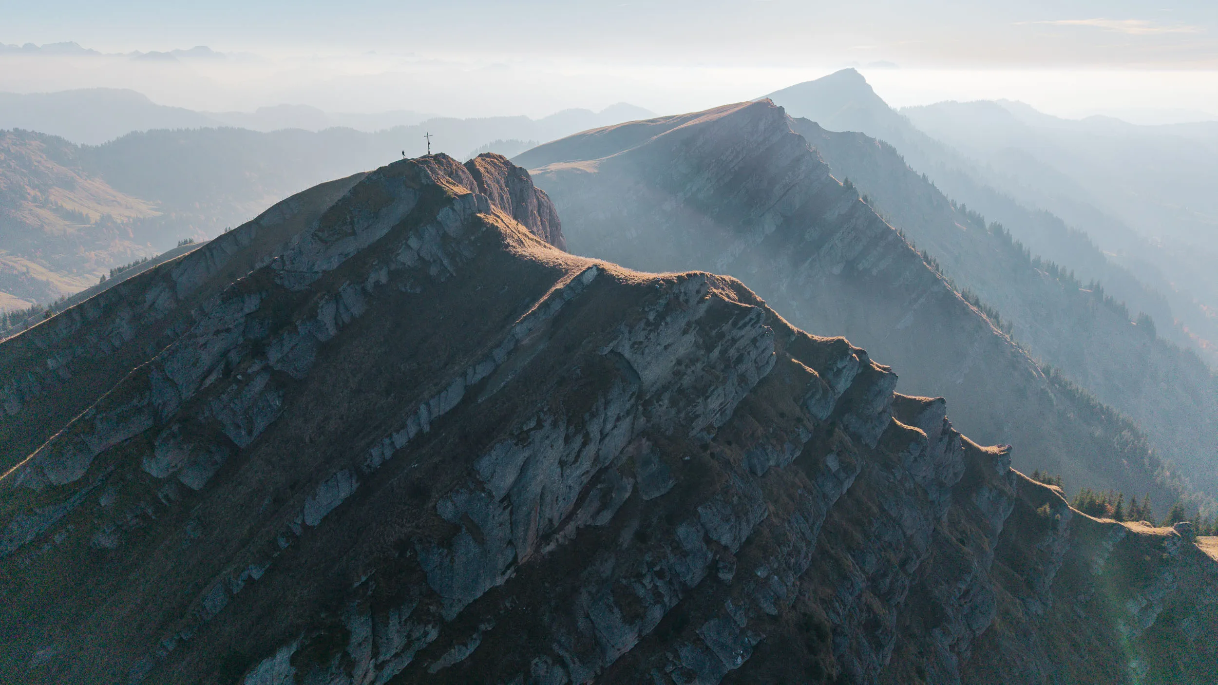 Schroffe Schichtfelsen eines Bergkamms wechseln zwischen Licht und tiefem Schatten