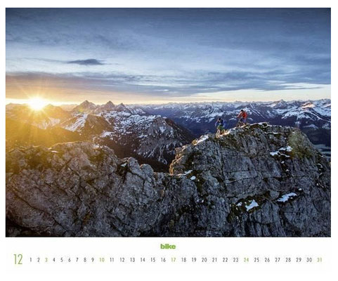 BIKE Kalenderseite Dezember mit Mountainbikern auf einem Felsgipfel bei Sonnenuntergang