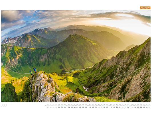 OUTDOOR Kalenderseite Juli mit Bergsteigern über einem grünen Allgäuer Hochtal im warmen Abendlicht